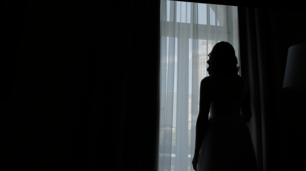 Silhouette of a bride in front of a window with a view of Warsaw - emotional moment of a wedding in Warsaw.